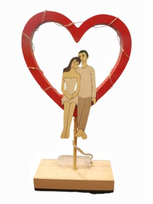 Cuore in legno con luci e coppia di innamorati